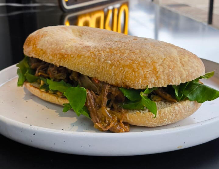 SERRANITO / sándwich de vacío desmenuzado, cebolla curada, rúcula, aderezo roma, papas fritas / $16990